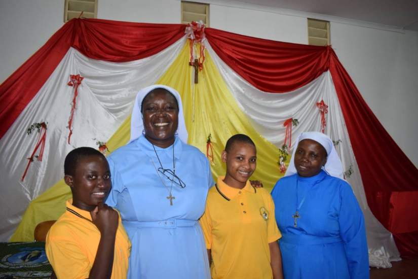 The Headmaster of Bigwa Secondary School in Morogoro, Tanzania poses with ASEC Executive Director Sr. Draru Mary Cecilia, LSMIG, Ph.D., who warmly embraces two recipients of ASEC scholarships to attend Bigwa.