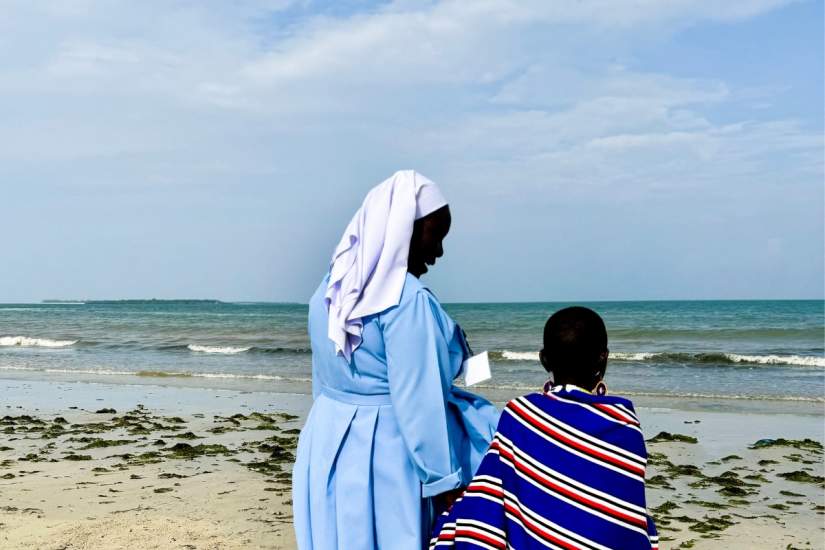 A bit cautiously, Joyce, 12 is guided by ASEC Executive Director Sr.Draru Mary Cecilia, LSMIG while seeing the ocean for the first time while at the 2024 SLDI Partner Workshop in Tanzania.
