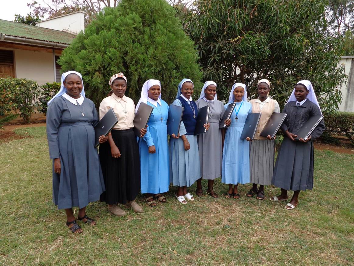 Sisters stand together at their HESA orientation presenting their new laptops (from L-R) Sr. Pelagia Chimpa, Sr. Magreth Kiria, Sr. Restituta Msemwa, Sr. Spesioza Massawe, Sr. Agripina Fidelis, Sr. Efrosina Mbiki, Sr. Venosa Mshana, Sr. Yustina Yilima