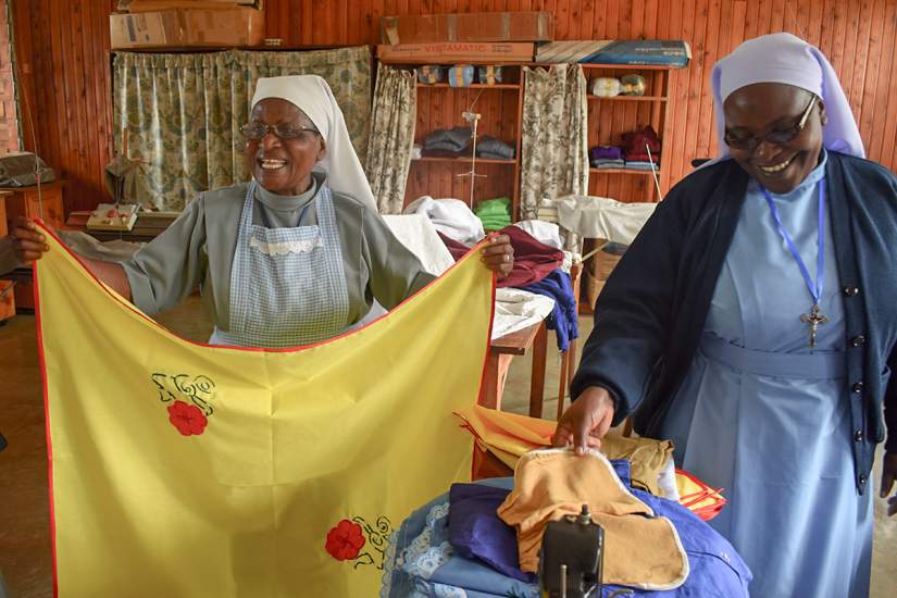 The CNDK sisters holding garments from their clothing and fabric manufacturing business in Huruma Rombo, Tanzania.