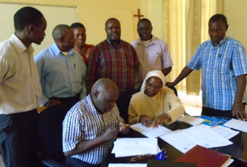 Prof. John Ssbuwufu, Principal Kisbubi Brothers University College signs the MOU. Looking on is Sr. Margaret Kubanze, LSOSF, AU, Secretary General, Uganda.