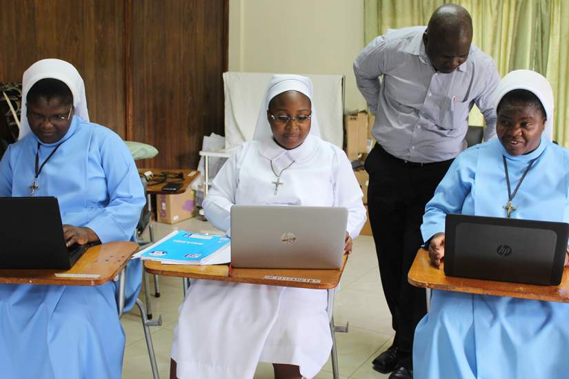 Sisters Christine, Sampa and Mwila participate in an exercise on computer and communication skills with the supervision of Mr. Adam Daka.