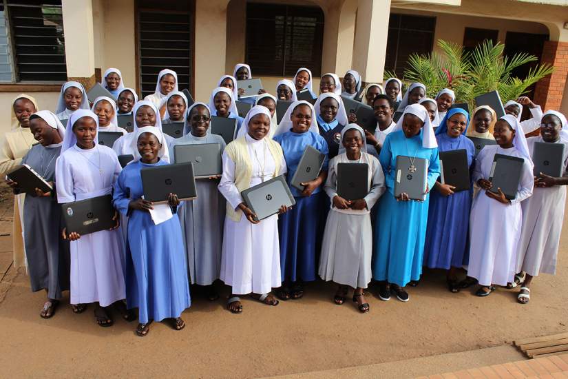 Sisters attending the online-onsite orientation at St. Augustine Institute Kampala, Uganda pose for a group photo holding their new laptops.