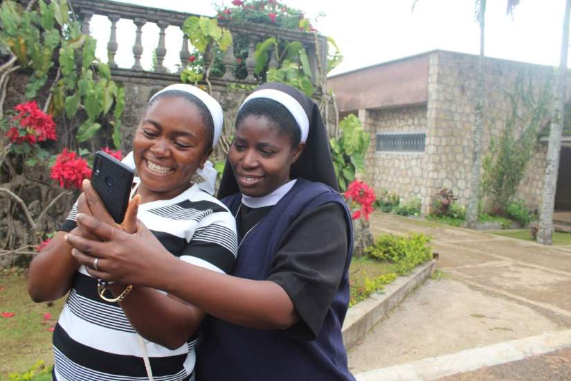 Sisters Odette and Cecilia exploring the technology of the phone at an SLDI workshop in Cameroon, 2019.