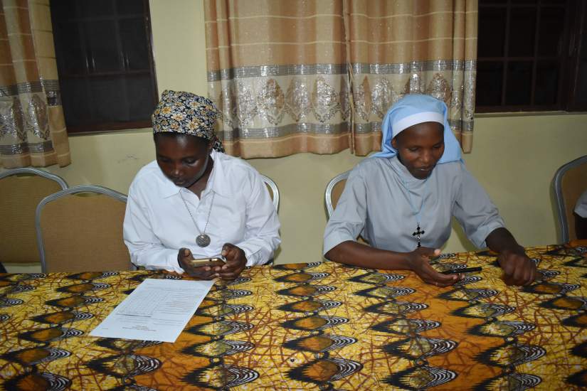 Sisters use mobile phones to fill in evaluation forms during HESA Orientation in Morogoro, Tanzania.