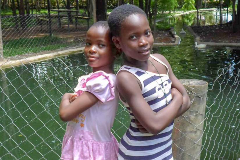 Younger sister Margaret (pink dress) and big sister Cecilia (stripes) pose for a photo. Because of the acts of Good Samaritans, Margaret and Cecilia are now thriving. Today the two sisters are very responsible, hardworking girls.