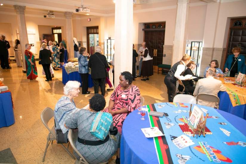 Guests connect over food and conversation surrounded by African-themed décor, including hand-carved giraffes and vibrant cloths from the communities ASEC serves.