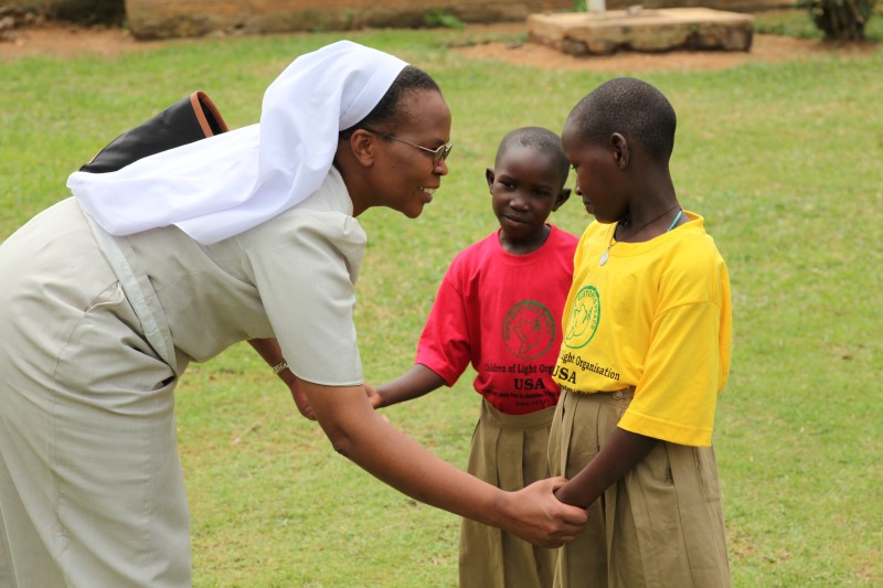 Sr. Jane crouches down to talk to two little boys.