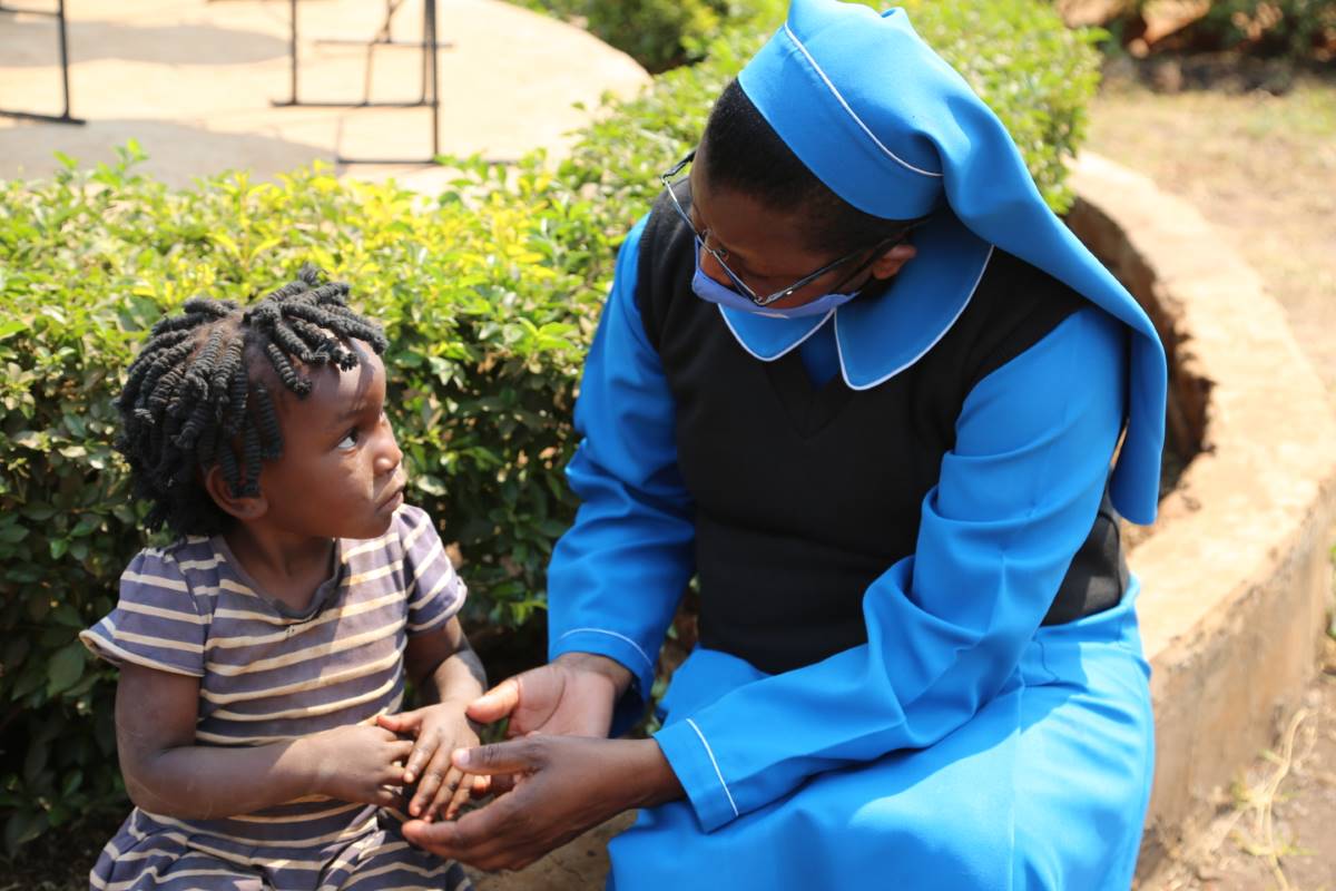 ASEC Program Director Sr. Juliana Zulu, RGS, shows the love and care of a sister to a little girl in Zambia.