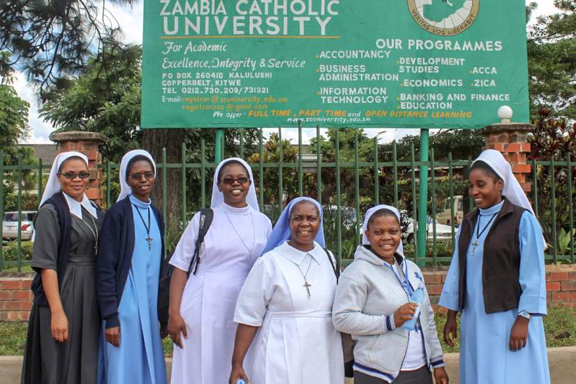 HESA students of Zambia Catholic University pose for a photo under their alma mater's sign.