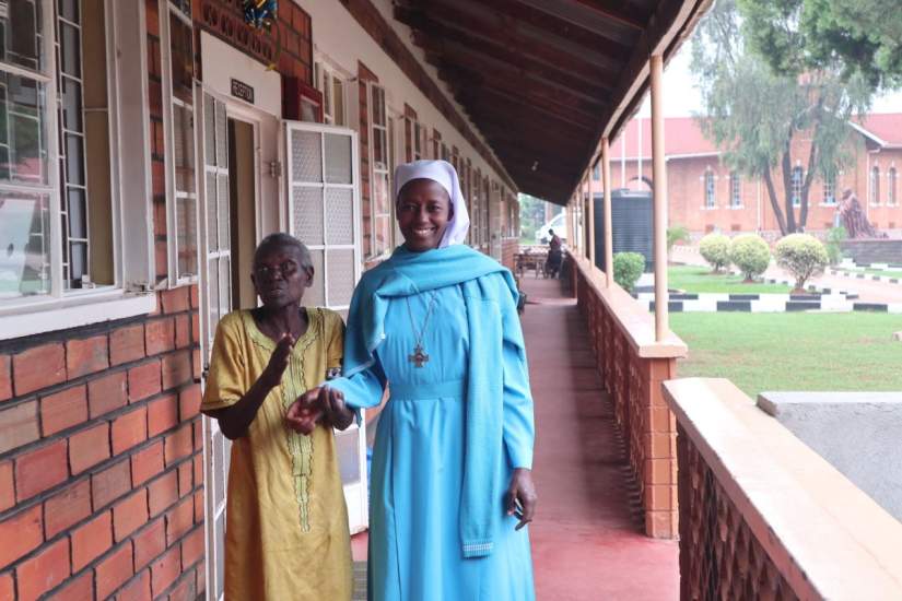 A Good Samaritan Sister walks with an elderly resident of Mapeera Home.