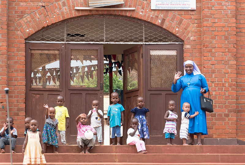 Mgolole Orphans waving on the stoop
