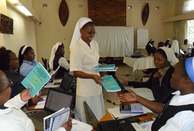 Sr Maureen Malashya distributing text books and Laptops to the SLDI Finance Track I at Kalundu Study Centre